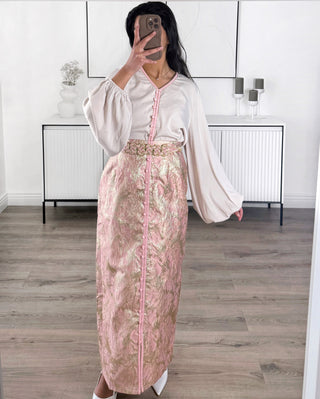 Caftan moderne deux pièces rose et doré composé d’un haut fluide à manches amples et d’une jupe longue brocart avec ceinture tressée.