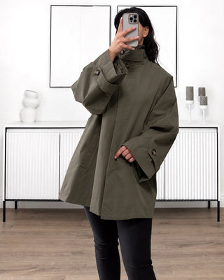 Trench mi-long mastour couleur kaki. Coupe oversize pour femme, avec col montant, fermeture zippée et manches longues.